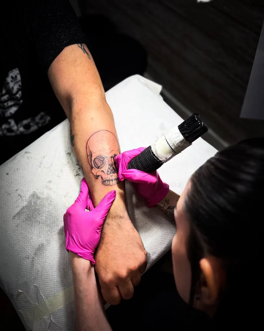 Alumna tatuando una calavera en un brazo durante las prácticas de la escuela ESAP de Madrid Alumna tatuando una calavera en un brazo durante las prácticas de la escuela ESAP de Madrid
