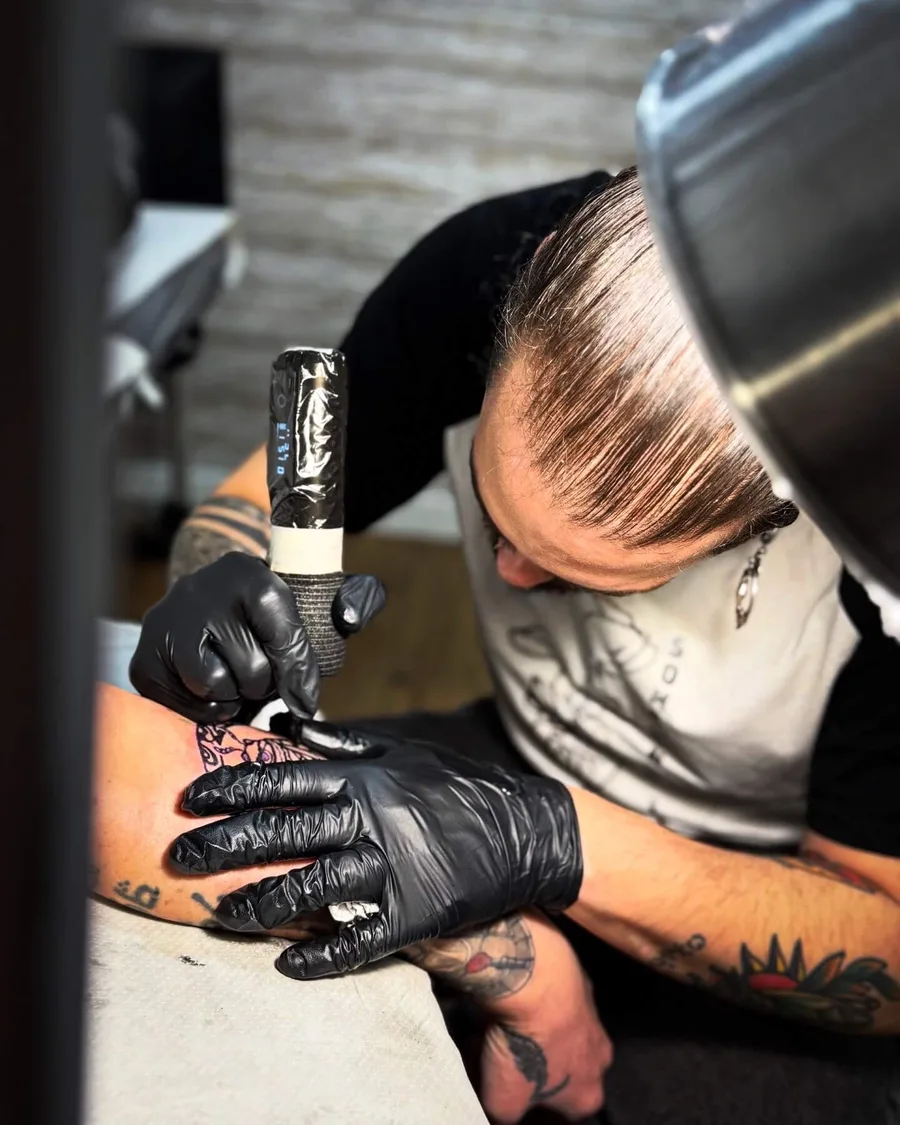 Alumna tatuando la nuca de una persona en las prácticas de la escuela ESAP de Madrid Alumna tatuando la nuca de una persona en las prácticas de la escuela ESAP de Madrid