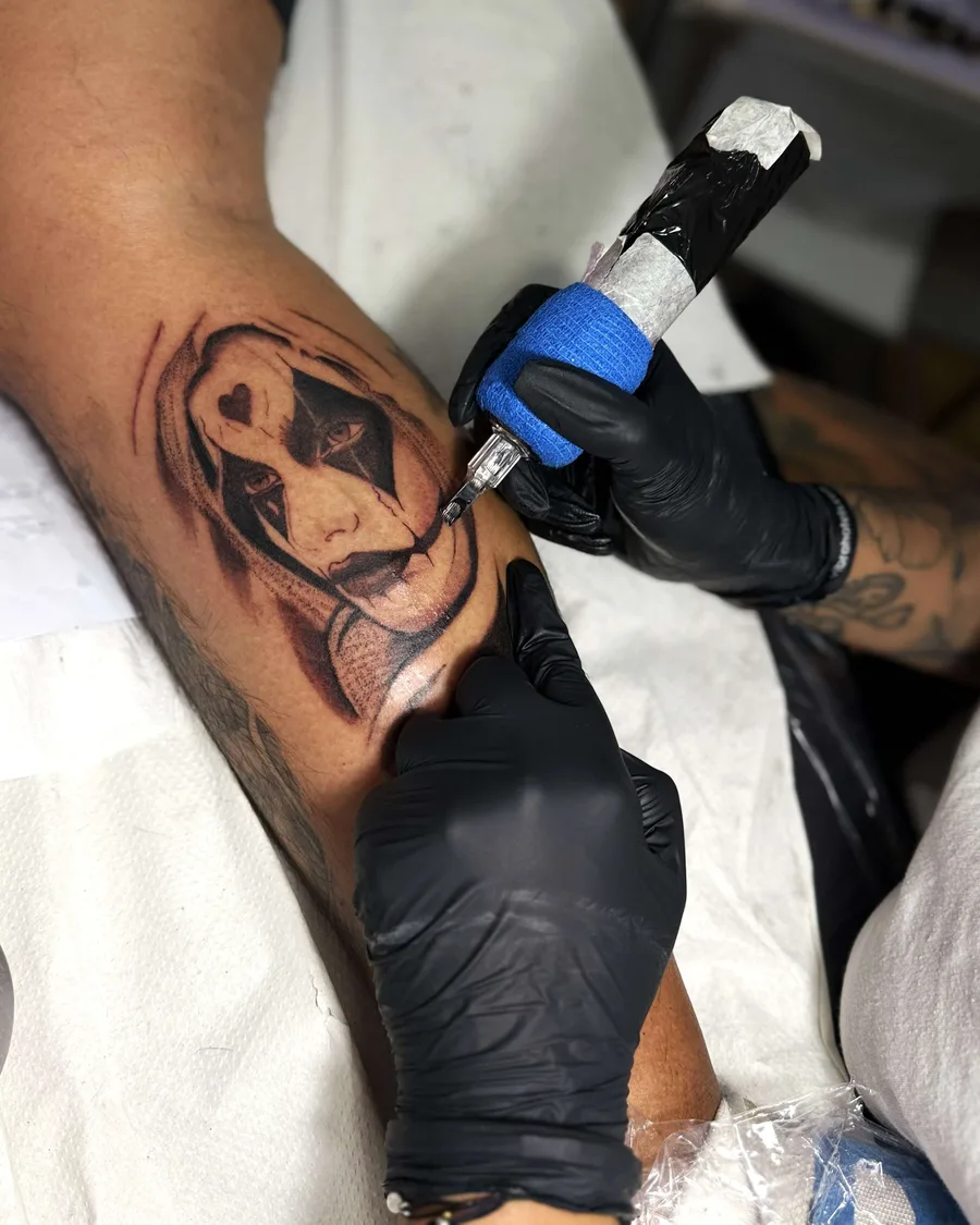 Alumna tatuando un retrato a color en un brazo en la escuela ESAP de Madrid