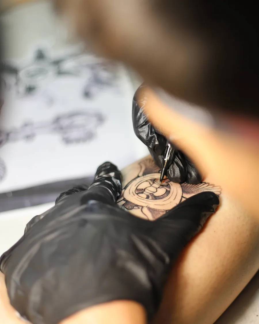 Alumno tatuando un diseño con guantes en la escuela ESAP de Madrid Alumno tatuando un diseño con guantes en la escuela ESAP de Madrid