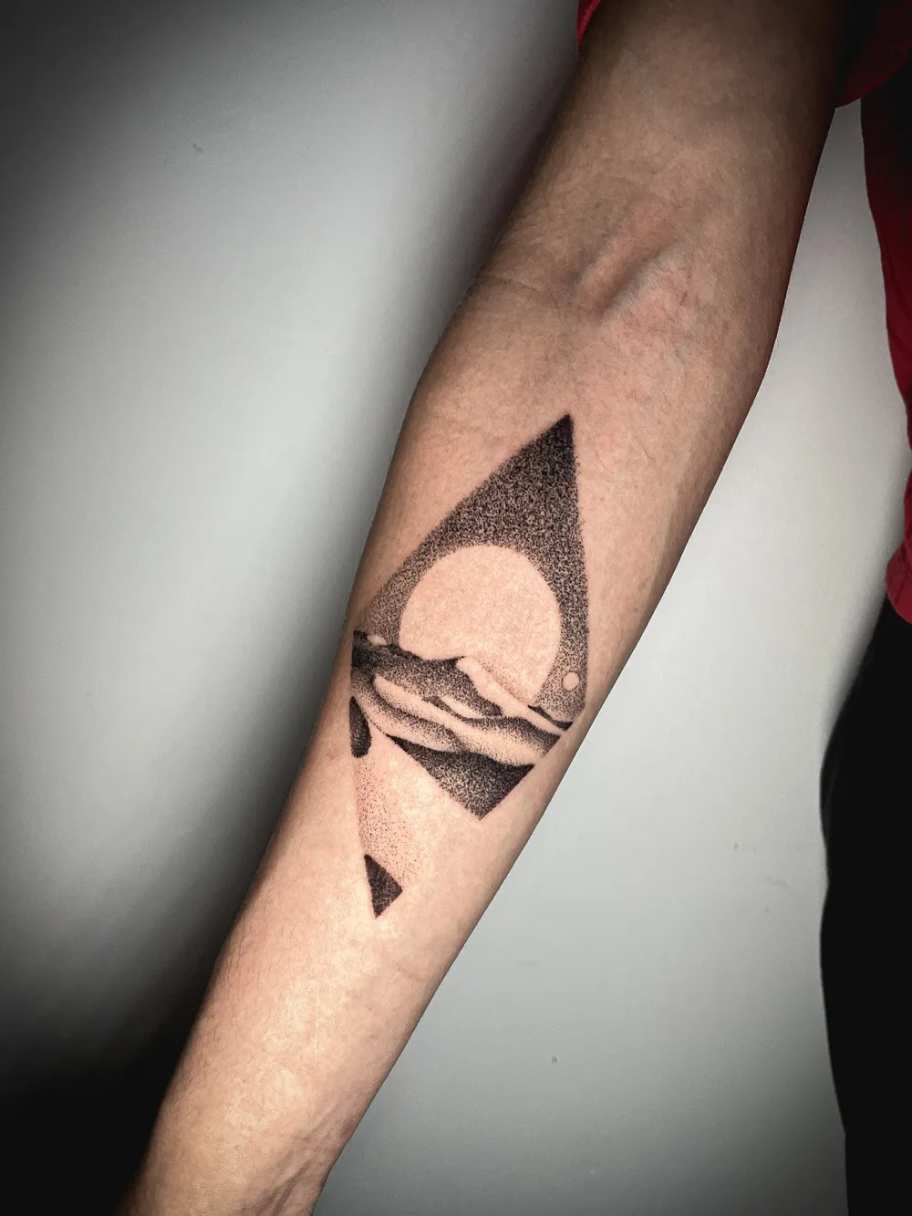 Tatuaje de puntillismo (dotwork) de un paisaje geométrico con sol, hecho en el seminario de ESAP Madrid