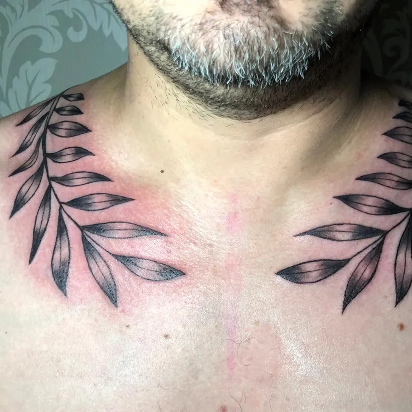 Tatuaje blackwork de ramas de laurel sobre las clavículas, hecho en ESAP Madrid