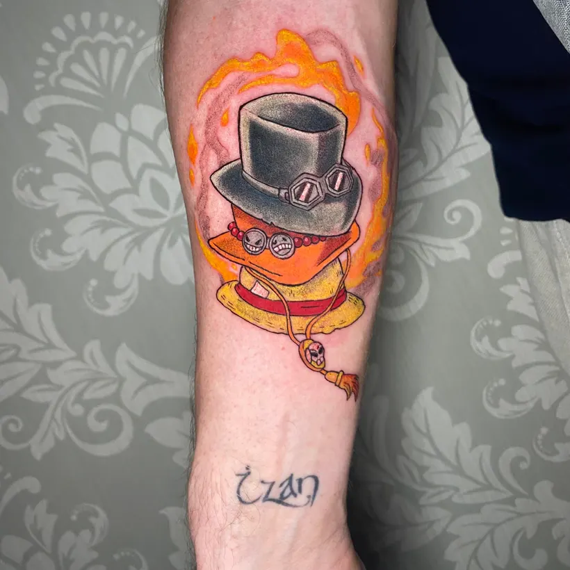 Tatuaje anime a color del sombrero de Sabo de One Piece en el antebrazo, hecho en ESAP Madrid Tatuaje anime a color del sombrero de Sabo de One Piece en el antebrazo, hecho en ESAP Madrid
